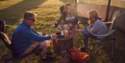 A family around a campfire cooking marshmallows