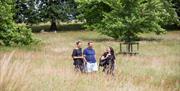 Three people walking through the parkland at Dyrham Park