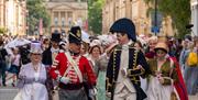 Two men and two women all dressed in Jane Austen-themed costumes leading a procession