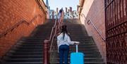 Person with suitcase in front of steps