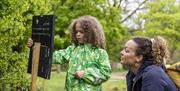 A child and parent looking at a trail sign in a garden.