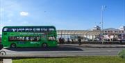 A green-coloured fully electric double decker bus owned by First Bus parked outside The Grand Pier in Weston-super-Mare, North Somerset