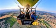 View of people in a balloon basket in the whilst in the air.