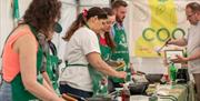 An image of people cooking at one of the demonstrations at Foodies Festival.