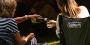 Two audience members sharing a bottle of wine at the Garden Theatre Festival in Bath.