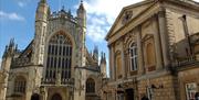 The front exterior of Bath Abbey on the left and The Roman Baths on the right.