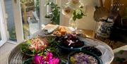 Persian food and flowers on a large basket tray on a kitchen cabinet.