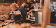 Two baristas serving customers behind the bar at Iford Manor Cafe