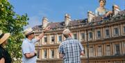 Tour guide discussing Jane Austen standing above and behind Bath architecture
