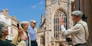 Tour guide discussing Bath Abbey in front of it with the tour group