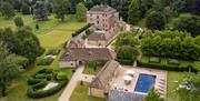 Another aerial shot of a manor, accompanying cottages, gardens, and a pool for rent.