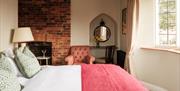 A double bed facing a large window, with a lamp and armchair alongside.