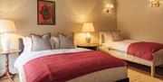 A twin bedroom with one double bed and one single bed.