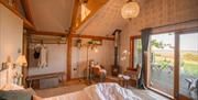 View of the interior of the bedroom in the treehouse and large sliding windows to the fields and porch