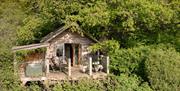 View of the exterior of the treehouse and the porch, surrounded by trees and nature