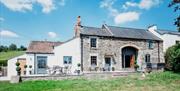 The exterior of a countryside house in a field.