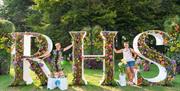 flower displays of the letters R H and S, two women in between them