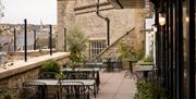 Outdoor terrace at Root Bath with several tables, chairs and potted plants