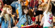 Children raising their hands at literature event