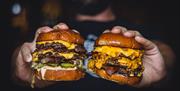 Hands holding two cheeseburgers