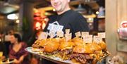Person holding a tray of burgers