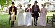 Five people walking in Queen Square, Bath, wearing period dress