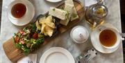 A sandwich, crisps and salad surrounded by tea and white crockery at The Abbey Tea Bar, Bath