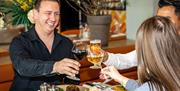 A group of people raising their glasses around a table inside The Orange Artichoke restaurant, based within the Apex City of Bath Hotel.