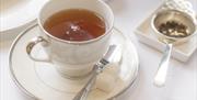A cup of tea on one of the interior tables in The Roseate Villa Bath's Henrietta Bar