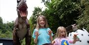 Children standing next to animatronic dinosaur model at Wookey Hole Caves