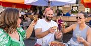 A group of people eating pizza outside