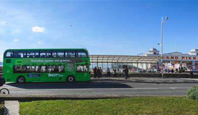 A green-coloured fully electric double decker bus owned by First Bus parked outside The Grand Pier in Weston-super-Mare, North Somerset