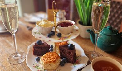 An image of a cream tea with two glasses of Prosecco on a table.