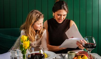 A woman and a girl looking at a menu in a restaurant.