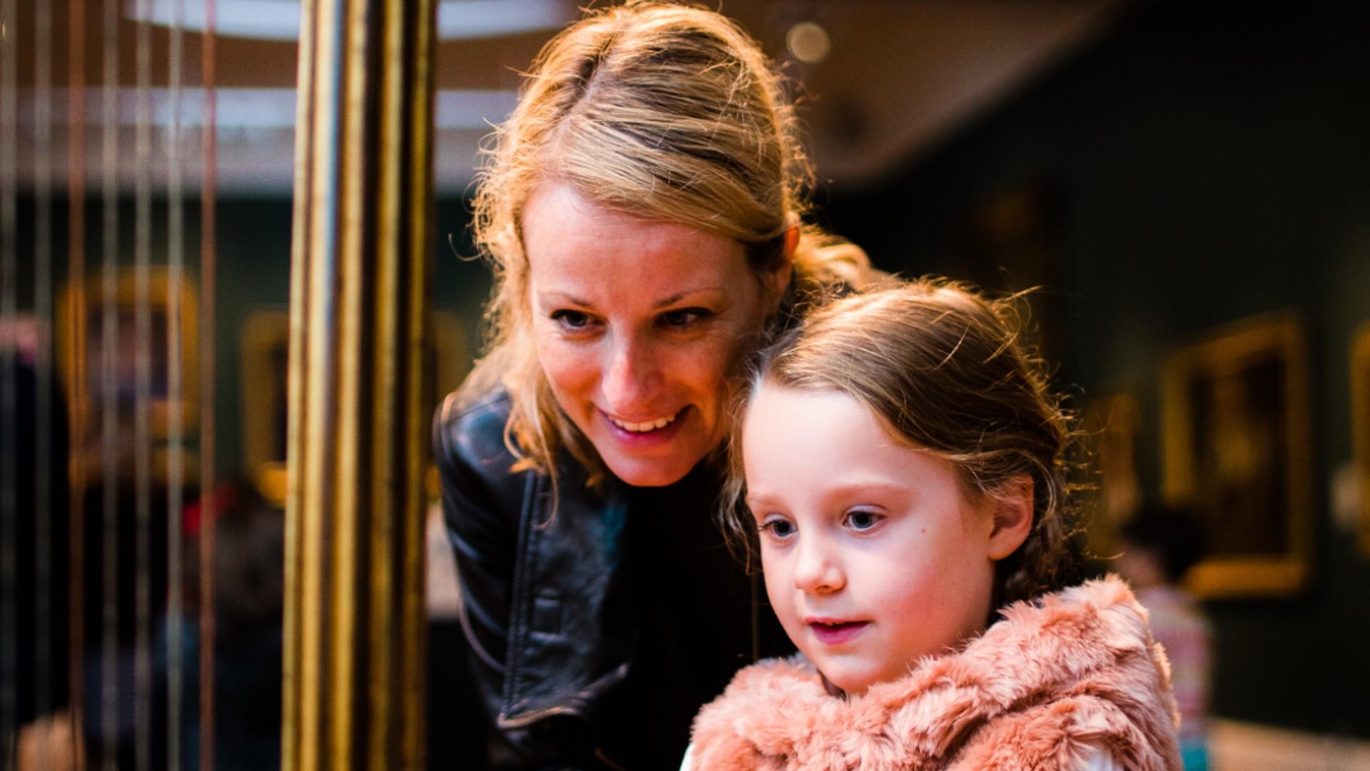 A mother and daughter looking at a museum exhibit together in Bath - Visit Bath