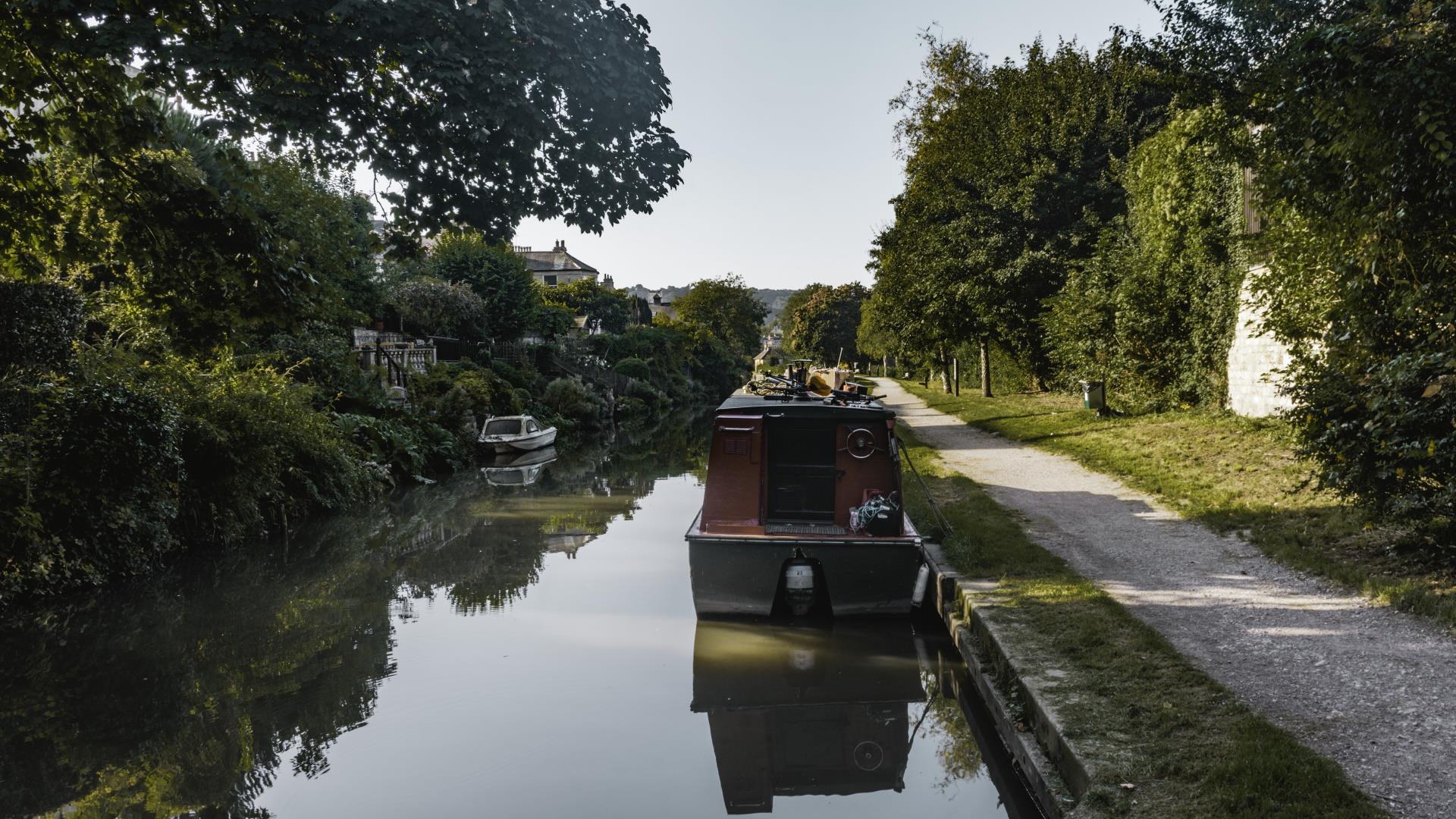 Canal with trees overhanging, a canal boat and tow path adjacent
