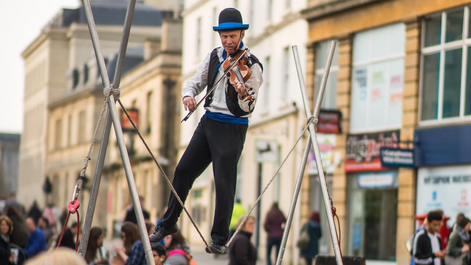 Man plays the violin whilst walking on a tightrope