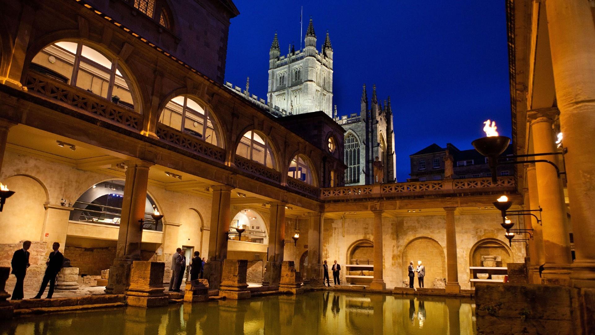 The Roman Baths at night with people enjoying the attraction