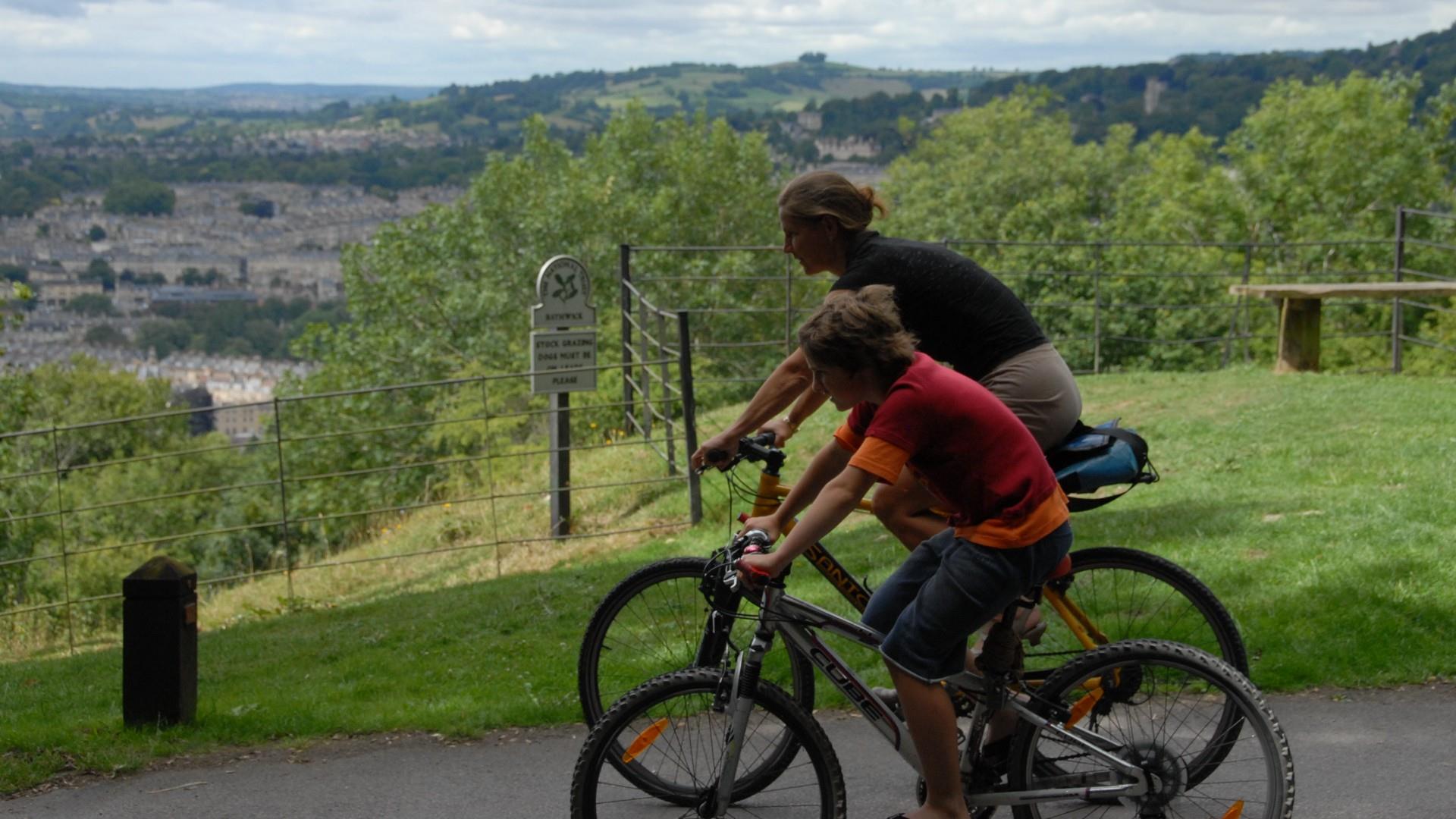 Woman and child cycling with Bath in the background