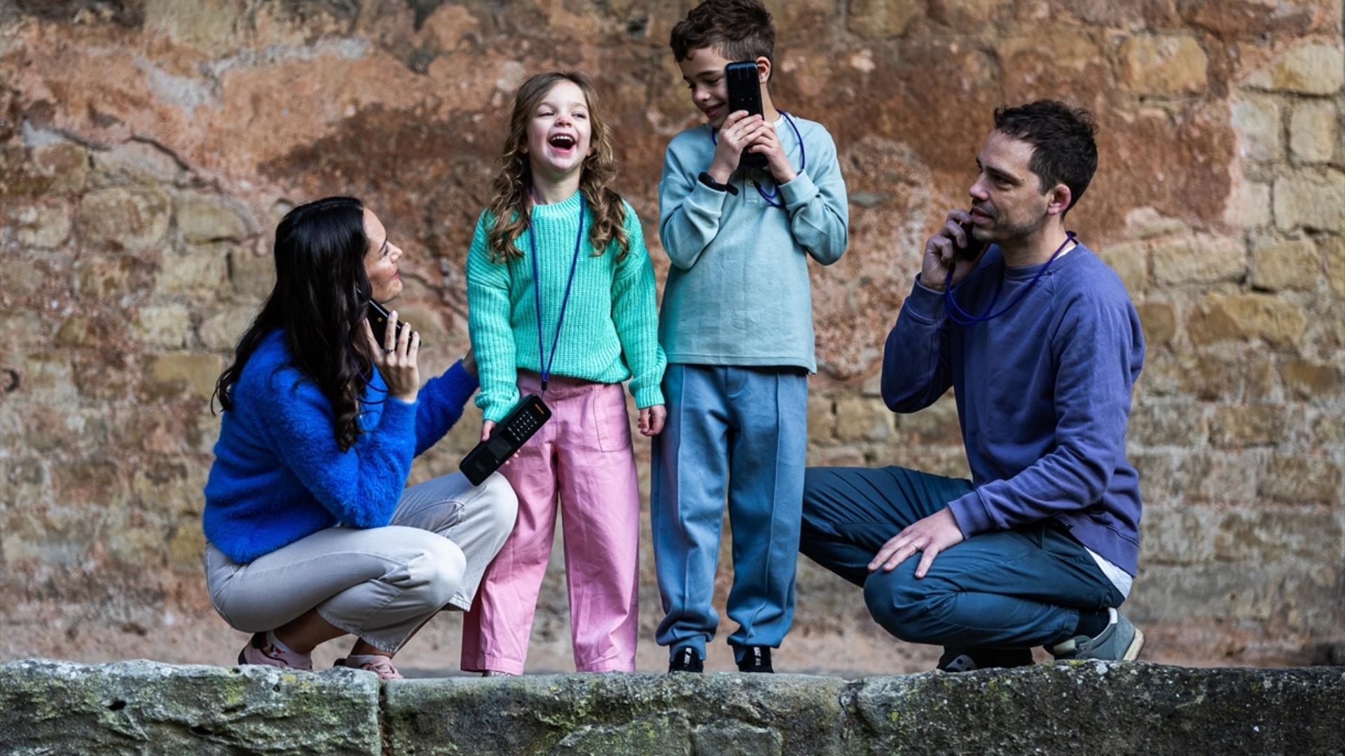 A family holding audio guides to their ears at The Roman Baths, Bath.