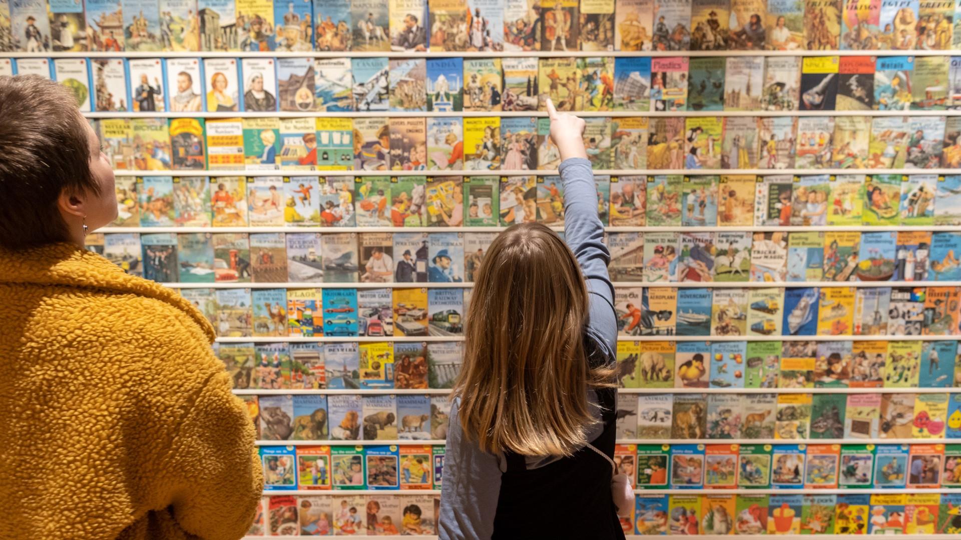Child looking at book covers on wall