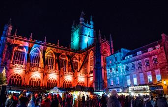 Bath Abbey lit in Christmas lights with market stalls in foreground
