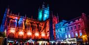 Bath Abbey lit in Christmas lights with market stalls in foreground
