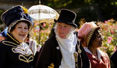 A man flanked by two women all wearing Jane Austen-themed costumes