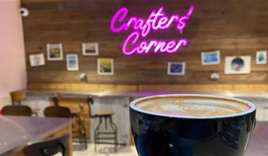 Crafter's Corner neon sign, coffee in front 