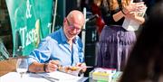 A man signing books and smiling