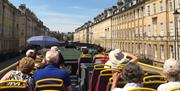 The top deck of a Tootbus Bath open-top bus going down Great Pulteney Street, Bath