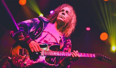A man playing the electric guitar on a stage