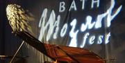A piano on a stage with the words 'Bath Mozartfest' projected on to a curtain in the background