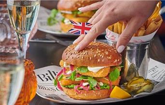 Fish burger and chips with Union Jack flag on bun.